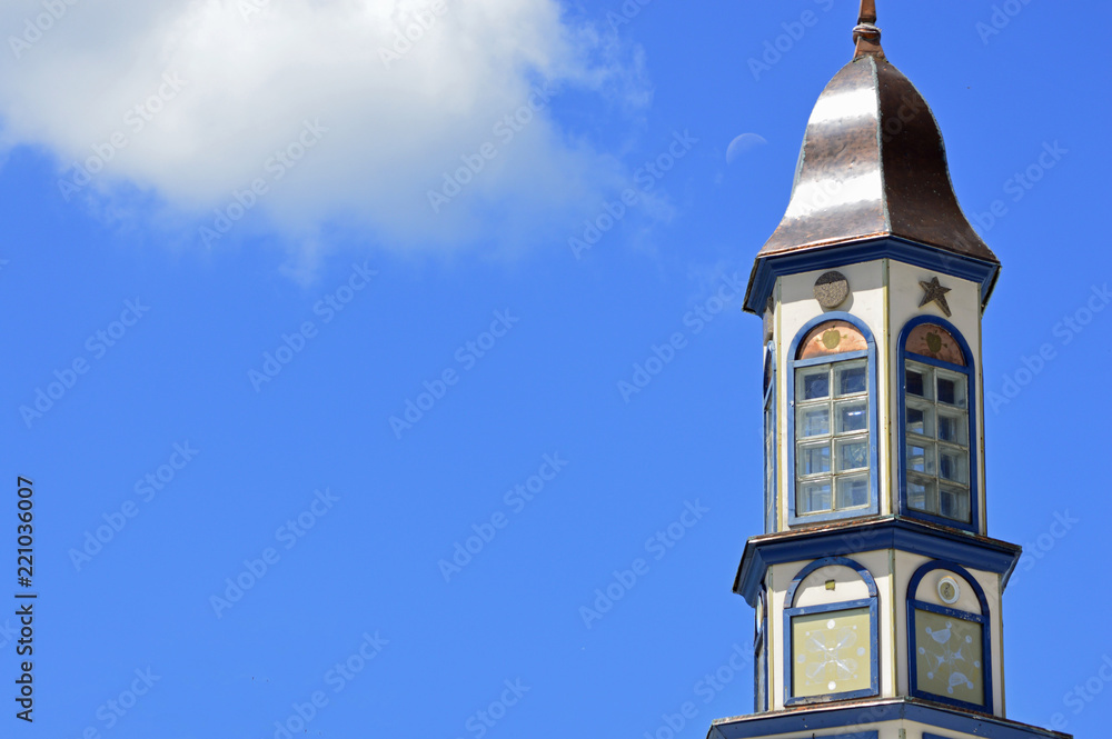 Interesting brass tower with the moon and clouds in a blue sky background Interesting brass tower with the moon and clouds in a blue sky background
