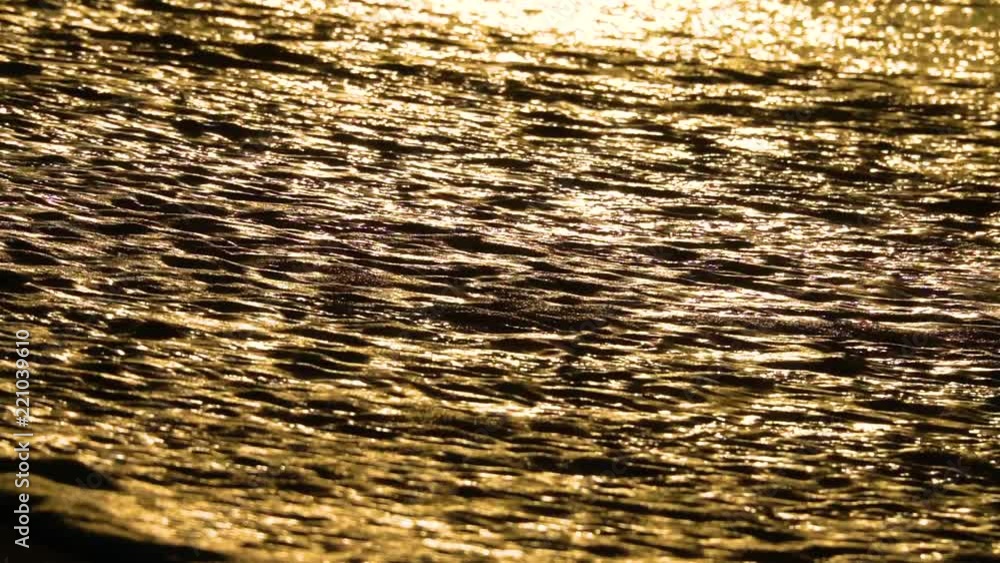 SLOW MOTION, CLOSE UP: Small waves glimmering in the golden sunset sweep the empty shore of a remote paradise island. Spectacular view of the calm ocean on a picturesque summer evening. Cinematic sea. SLOW MOTION, CLOSE UP: Small waves glimmering in the golden sunset sweep the empty shore of a remote paradise island. Spectacular view of the calm ocean on a picturesque summer evening. Cinematic sea.