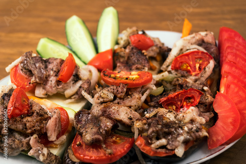 Vegetable dish with meat from baked eggplant with tomatoes, carrots and onions, and pieces of fried meat, sliced cucumbers and fresh tomatoes.