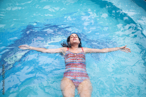 Woman in in pool with orange swimsuit