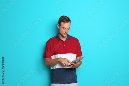 Young man with tablet on color background
