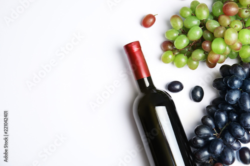 Fresh ripe juicy grapes, bottle of red wine and space for text on white background, top view