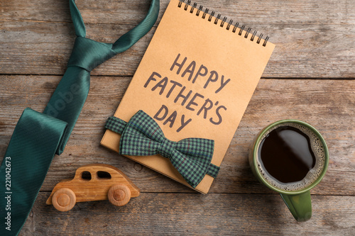 Flat lay composition with notebook, cup of coffee and accessories on wooden background. Father's day celebration
