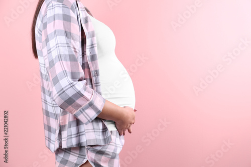 Young pregnant woman against color background, closeup. Space for text