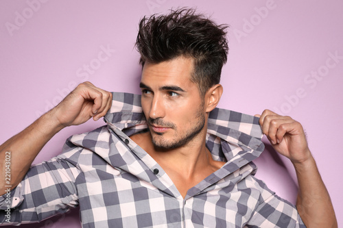 Young man with trendy hairstyle posing on color background