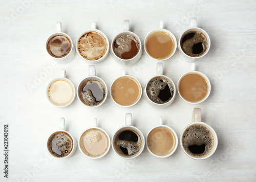 Many cups with tasty aromatic coffee on wooden table, flat lay