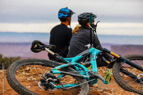 Bild auf Leinwand A Young Mountain Biking Couple Takes A Minute To Take In The Scenery