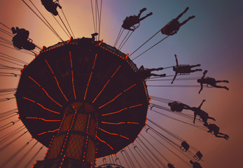 beautiful fair sunset photo of a swing ride full of people in silhouette