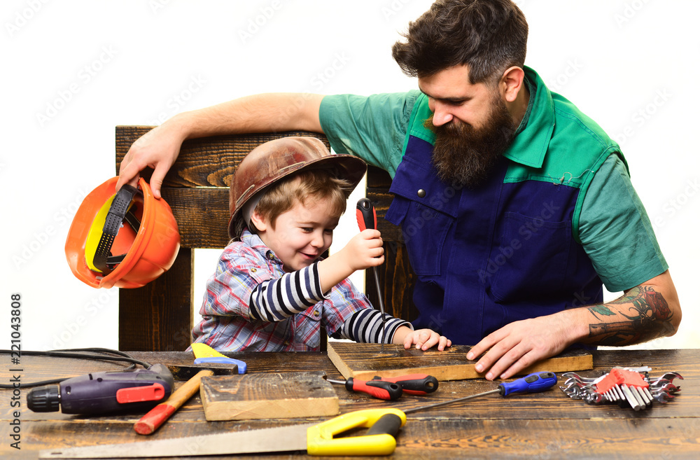 Father&son in workshop repairing. Cute boy exploring tool. Fatherhood concept. Dad&son child working with tools. Parent with busy small son. Daddy with little son in protective helmet with screwdriver Father&son in workshop repairing. Cute boy exploring tool. Fatherhood concept. Dad&son child working with tools. Parent with busy small son. Daddy with little son in protective helmet with screwdriver