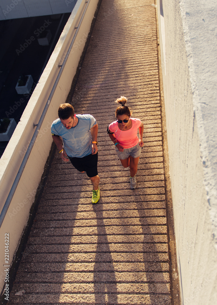 Athletic couple running on sunset in the city. Stay fit concept urban. Athletic couple running on sunset in the city. Stay fit concept urban.
