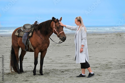 Woman patting horse on beach by the sea. Sand beach in Olympic National Park. Olympia. Washington. United States of America.