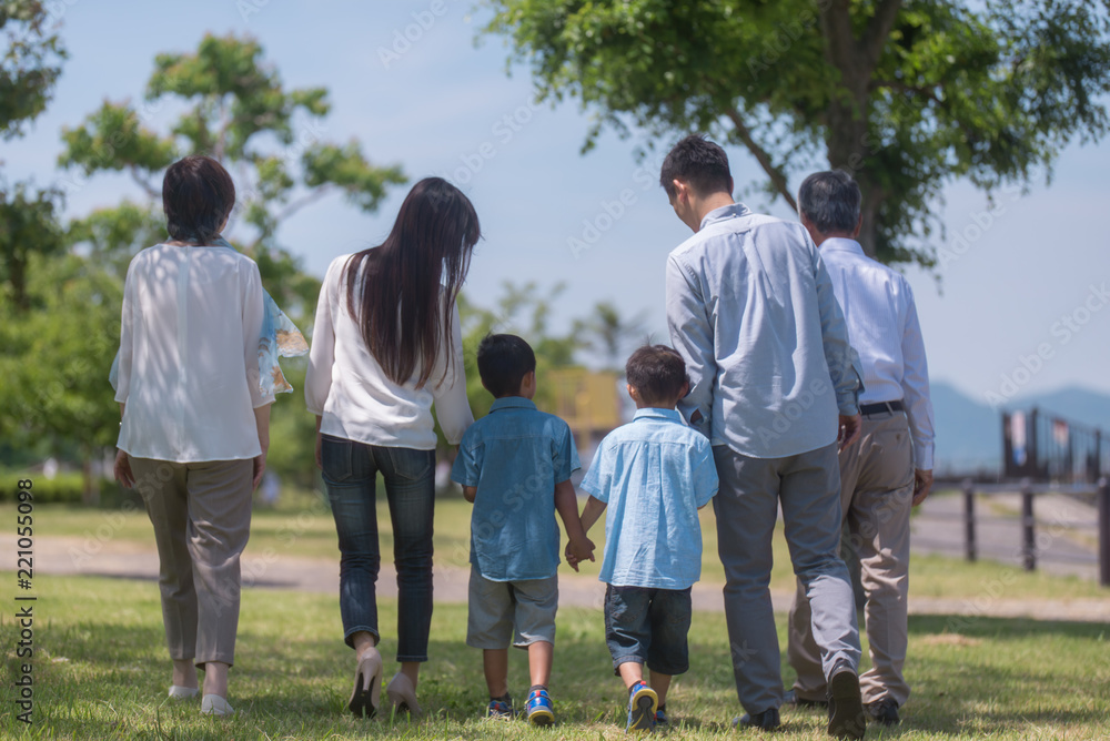 手を繋いで公園を歩く三世代家族の後ろ姿 手を繋いで公園を歩く三世代家族の後ろ姿