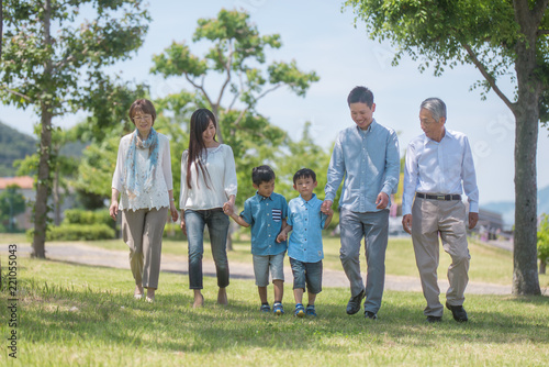 手を繋いで公園を歩く三世代家族 © tomoco_sozai