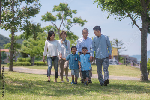 手を繋いで公園を歩く三世代家族