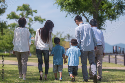 手を繋いで公園を歩く三世代家族の後ろ姿