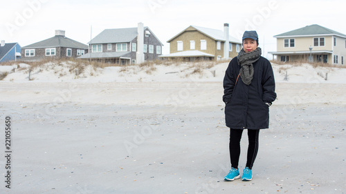 Woman on beach standing infront of houses