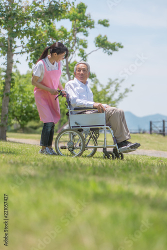 車椅子のシニア男性と介護スタッフ © tomoco_sozai
