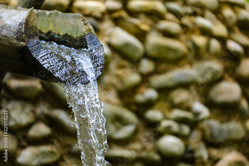Принти на полотні water flows from a wooden pipe or water gushing out of the pipe close up