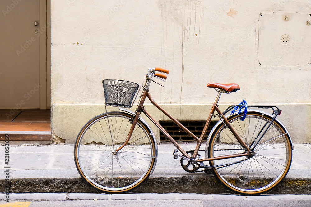 Old retro bicycle standing on a street in Florence, Italy by a wall Old retro bicycle standing on a street in Florence, Italy by a wall
