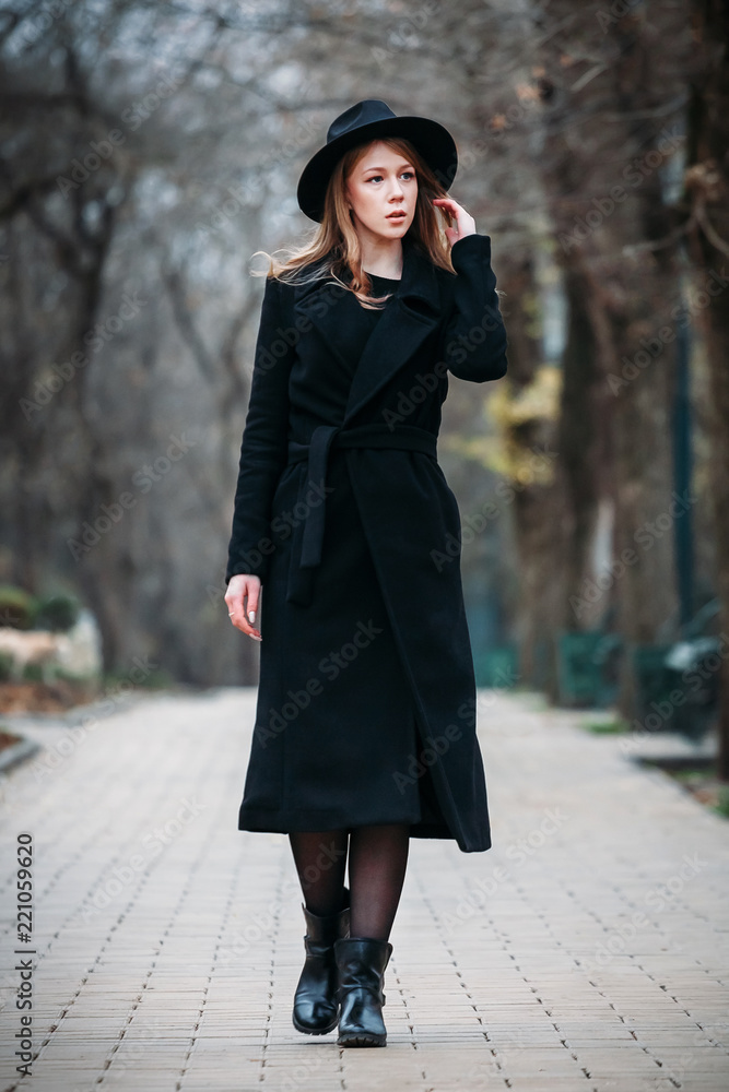 Outdoor portrait of a romantic, pretty elegant business of a long-haired woman, enjoying a stroll through the city. Photo of a adorable girl in a hat with curly hair