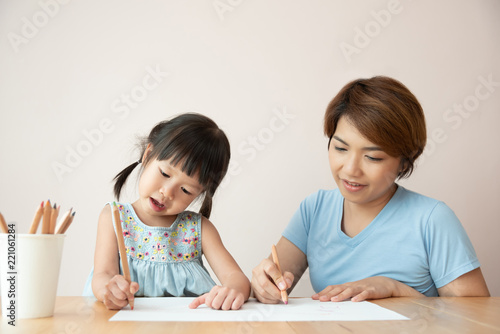 Happy Asian Mother and daughter drawing together.