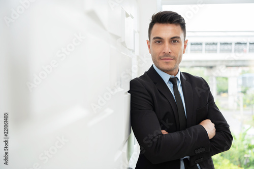 Successful Businessman standing over white wall.