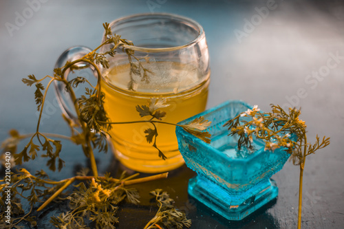 Close up of best home remedy for hair fall i.e. Coriander juice with some water apply to hair daily thrice or twice a week and see guaranteed result on wooden surface in dark gothic colors.