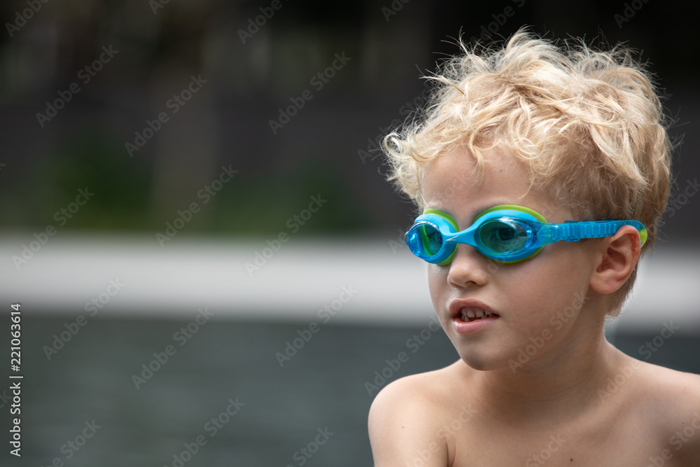Young boy wearing goggles at the poolside