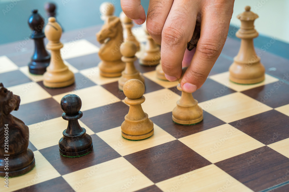 Hand moving a wooden chess figure on a chess board Hand moving a wooden chess figure on a chess board