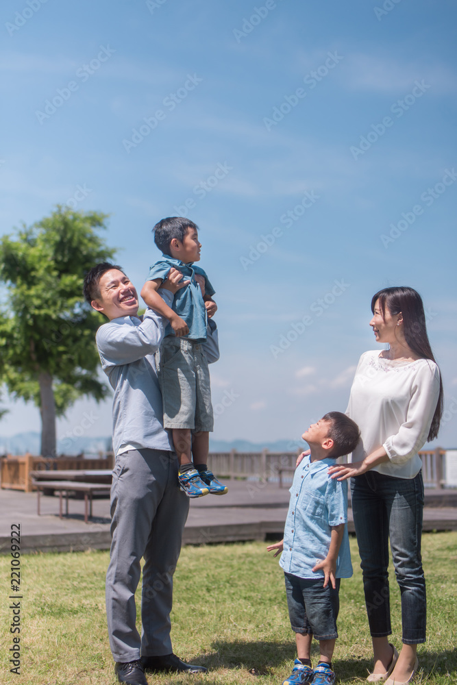 公園で息子を抱き上げるお父さんと微笑む家族