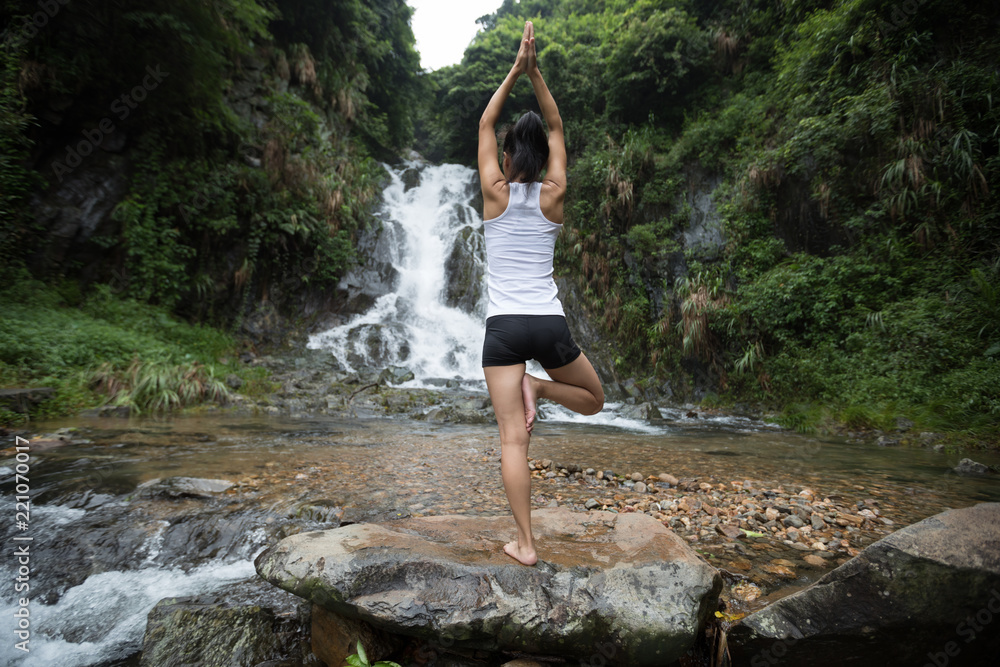 Young woman practice yoga near waterfall in forest Young woman practice yoga near waterfall in forest