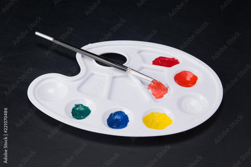 on a dark background, on a white palette of colored paints on a dark background, on a white palette of colored paints