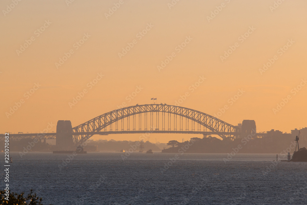Sydney Harbour Bridge in a hazy sunset sky.