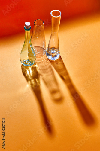 Empty glass vases with long shadows on a doutone red yellow paper background. photo