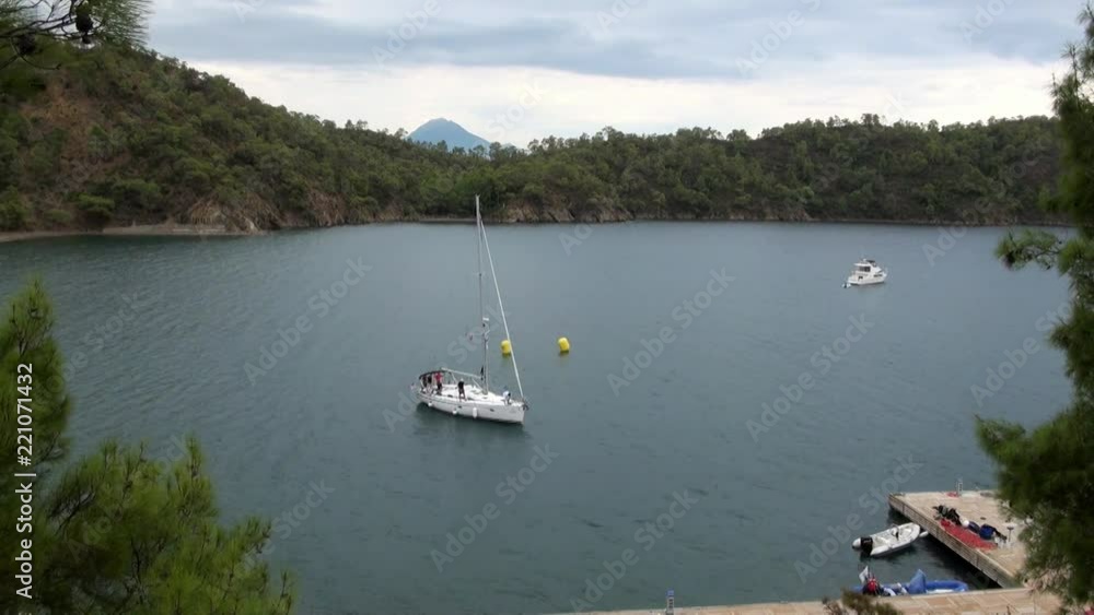 White yacht with people swims to the pier in the bay. Marine life style of travel by sea water. Beautiful seascape and unique coastline landscape. White yacht with people swims to the pier in the bay. Marine life style of travel by sea water. Beautiful seascape and unique coastline landscape.