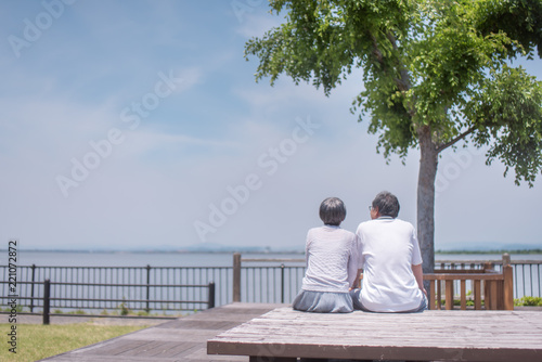 公園のベンチに座るシニア夫婦の後ろ姿