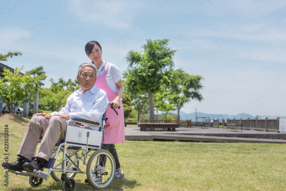 車椅子のシニア男性と女性介護スタッフ 車椅子のシニア男性と女性介護スタッフ