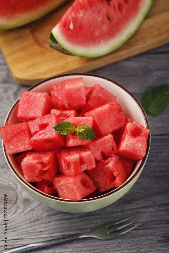 Full plate of sliced pieces of ripe watermelon with mint on a wooden table Full plate of sliced pieces of ripe watermelon with mint on a wooden table