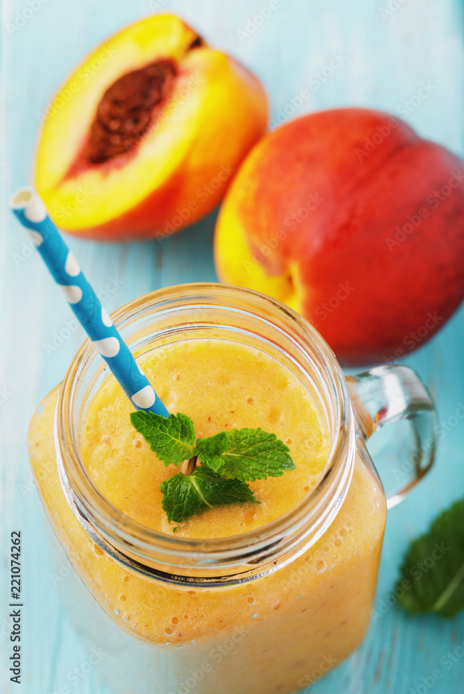Smoothies cooked from ripe peaches in a transparent jar with fruit on a wooden table Smoothies cooked from ripe peaches in a transparent jar with fruit on a wooden table