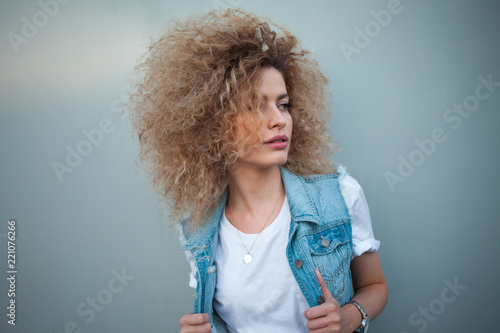 Young attractive woman with very lush hair. Portrait of a beautiful girl in denim vest