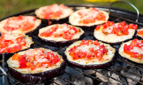 Eggplant with tomato and parmesan cheese on BBQ vegan grill.