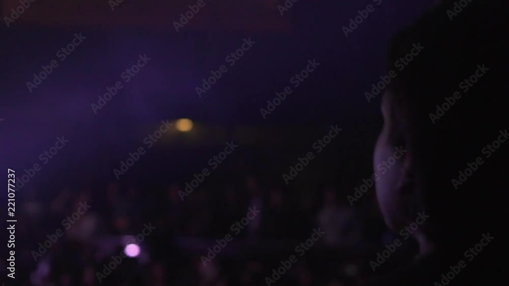 Mujer baila levantando una mano hacia el escenario en concierto.