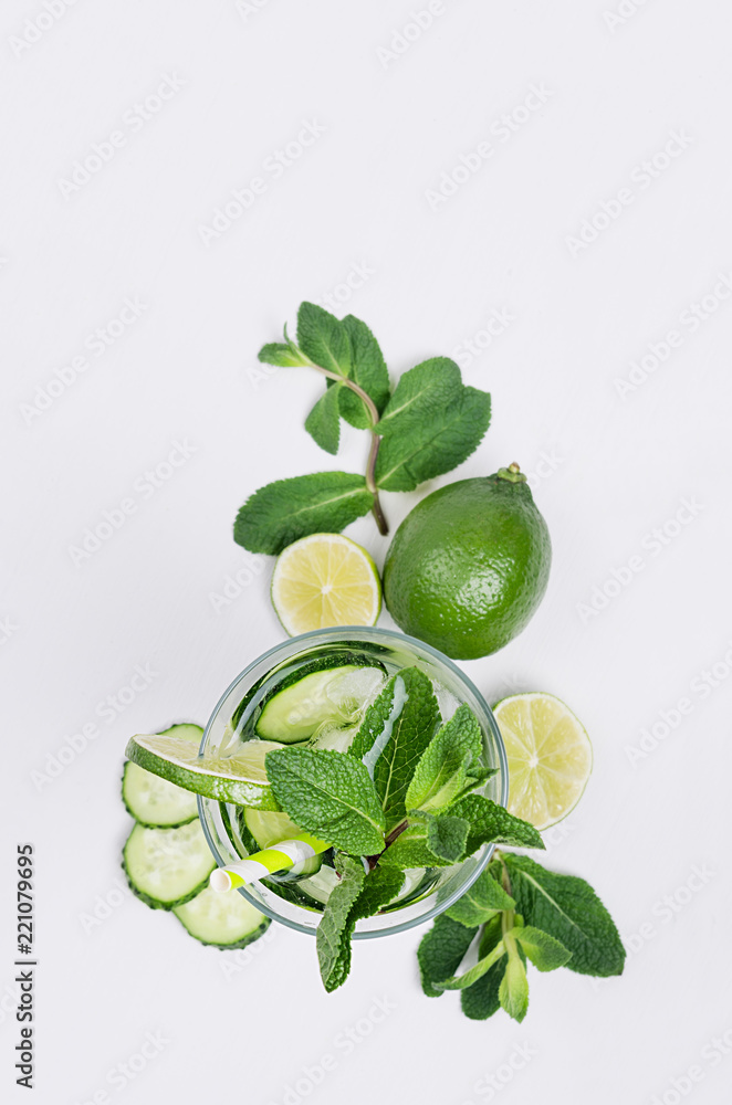 Ingredients for cooking cold green spring drink with cucumber, pieces of lime, fresh leaves mint and ice cubes on soft white background, top view. Ingredients for cooking cold green spring drink with cucumber, pieces of lime, fresh leaves mint and ice cubes on soft white background, top view.