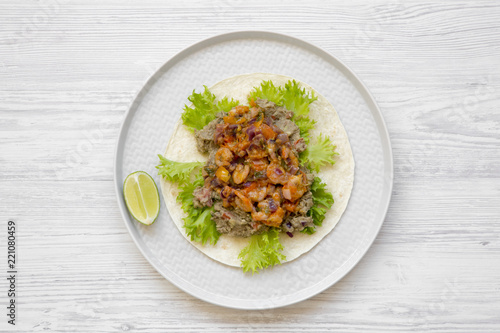 Shrimp taco with lime on round plate over white wooden background, top view. Flat lay, overhead, from above. Mexican food.