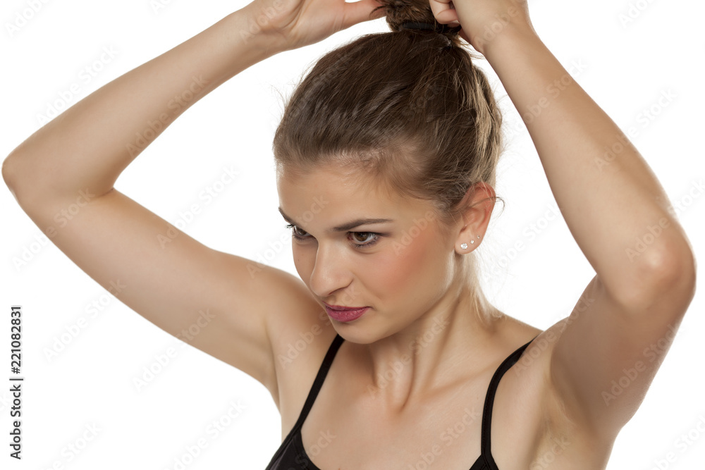 Profile of young woman tightening her hair in a bun on white background