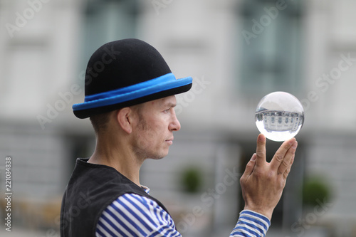 Transparent magic ball with reflection in the hands of a clown © Anna Jurkovska