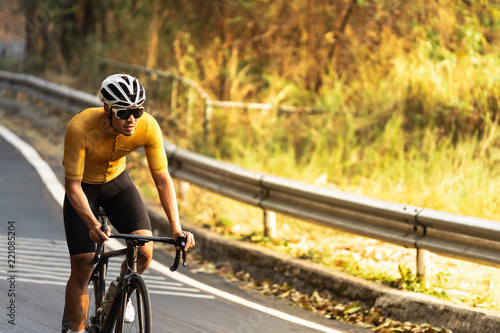 Asian man is cycling road bike. morning ride uphill on the road.