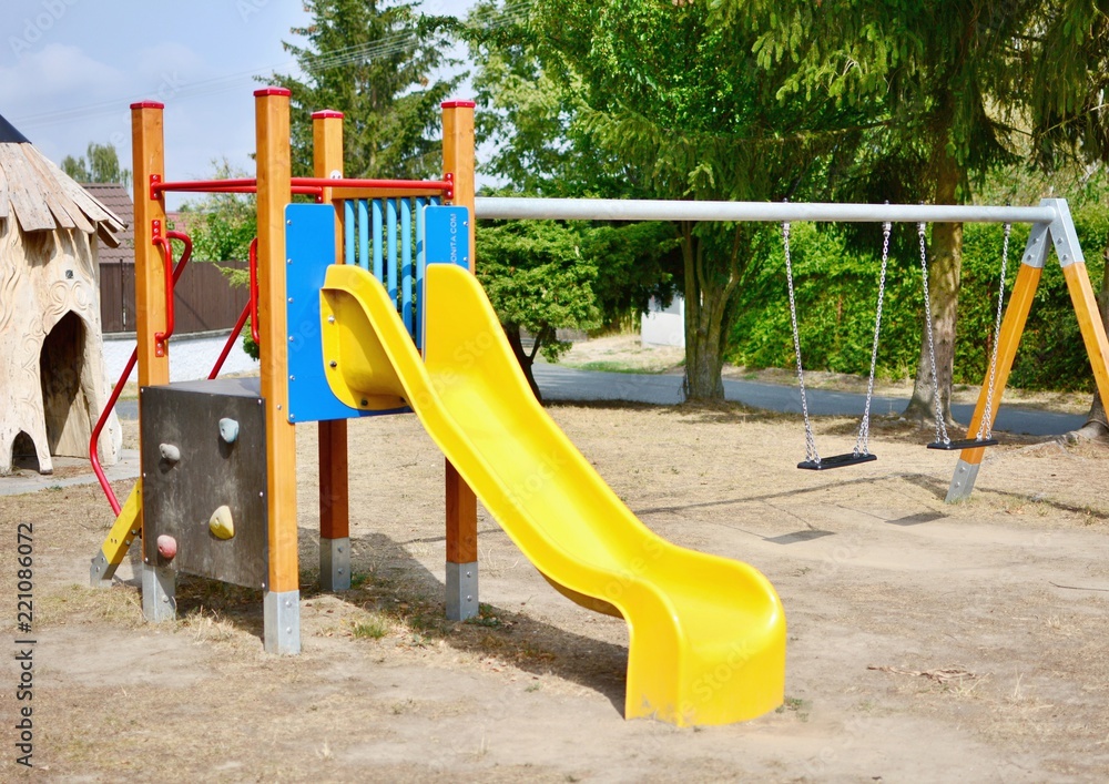 Yellow slide and chain swings in the empty playground. Yellow slide and chain swings in the empty playground.