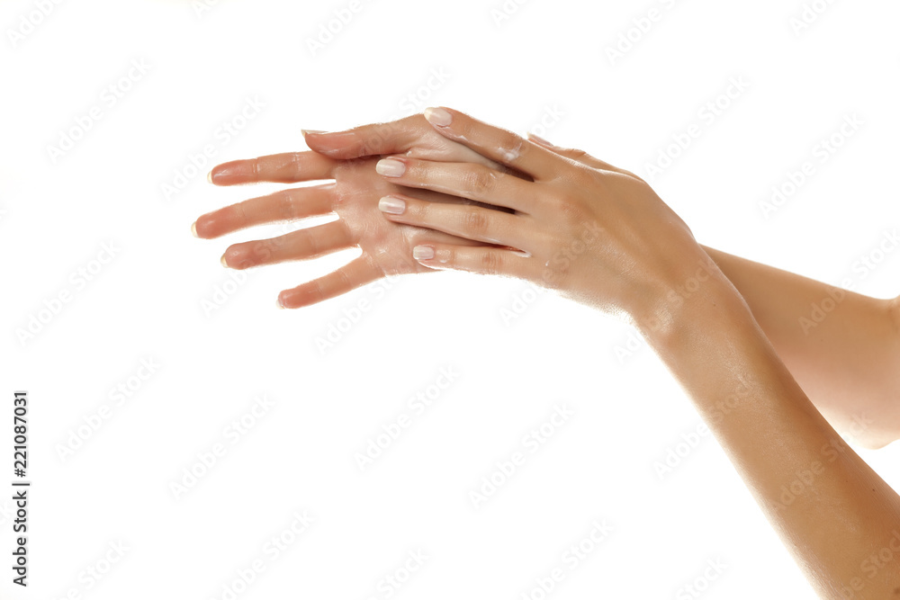 closeup of female hands applying hand cream on white background