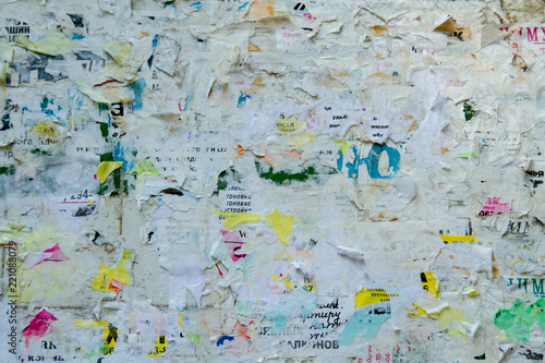 Board with tattered ads. A lot of ragged ads. Ragged paper ads. Advertising signboard with torn paper.